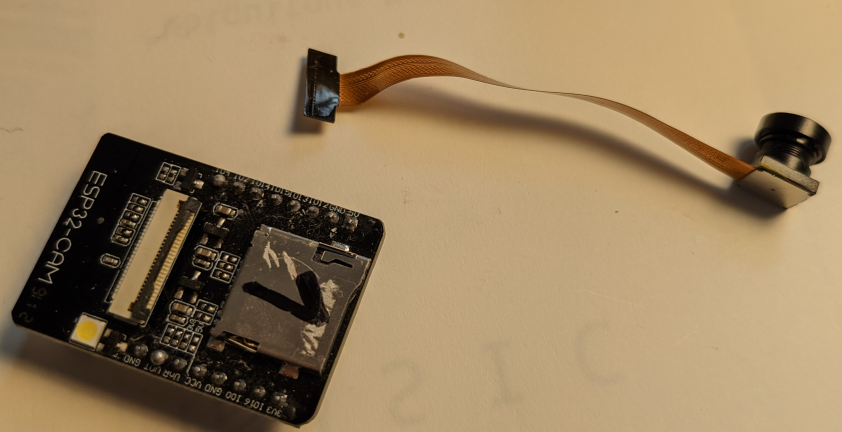 ESP32-CAM Board mit Kamera mit langem Flachbandkabel und einer Markierung der Hotspotnummer (hier 1 für hotspot1 als Beispiel) auf dem SD-Karten-Slot.